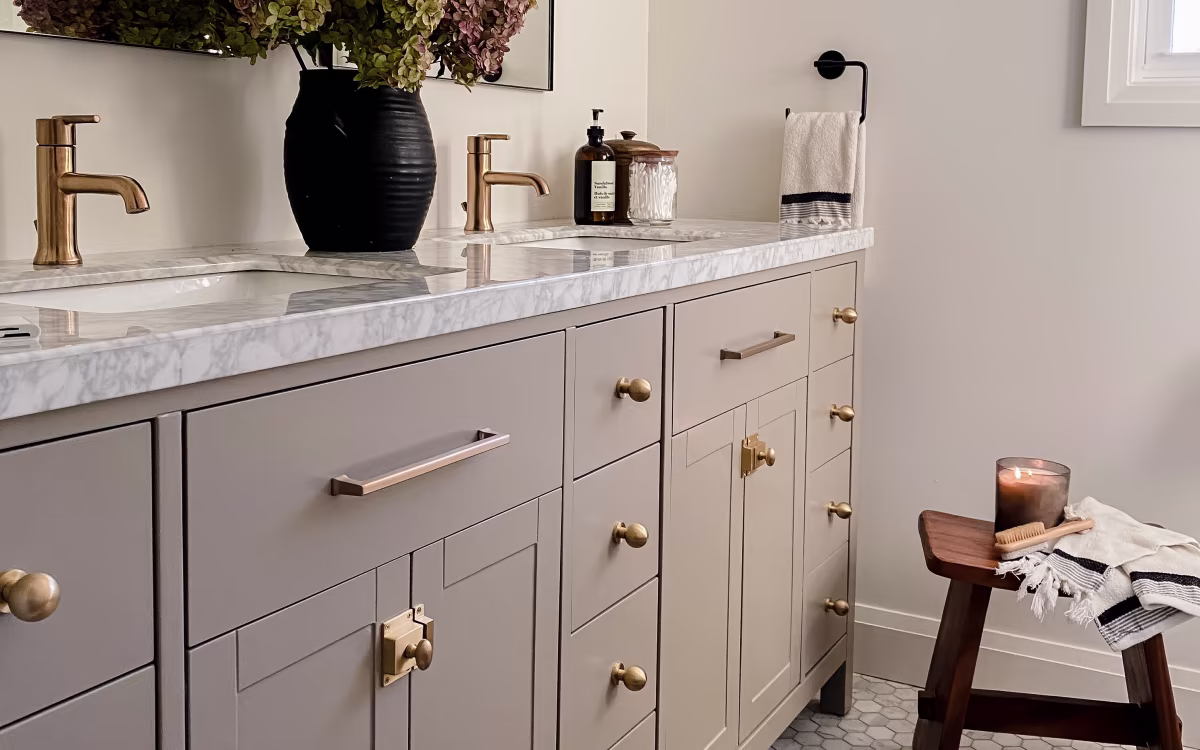 Hands installing brushed gold cabinet handle on white refinished door